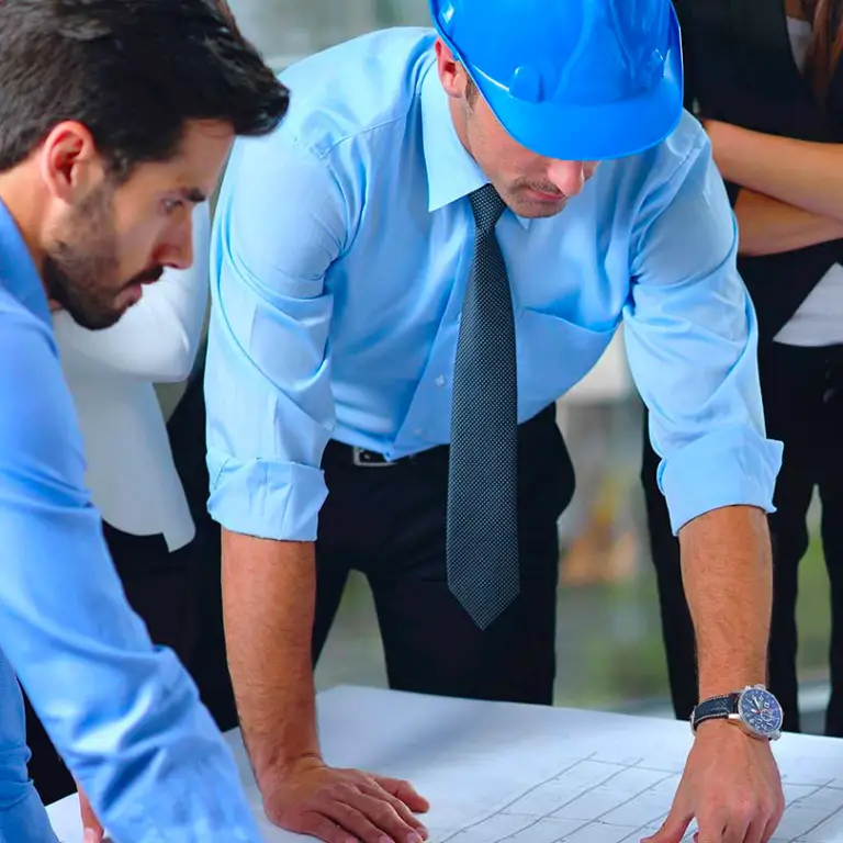 Réunion de professionnels autour de plans de construction, illustrant les solutions de financement sur mesure pour PME suisses proposées par Ecofina.